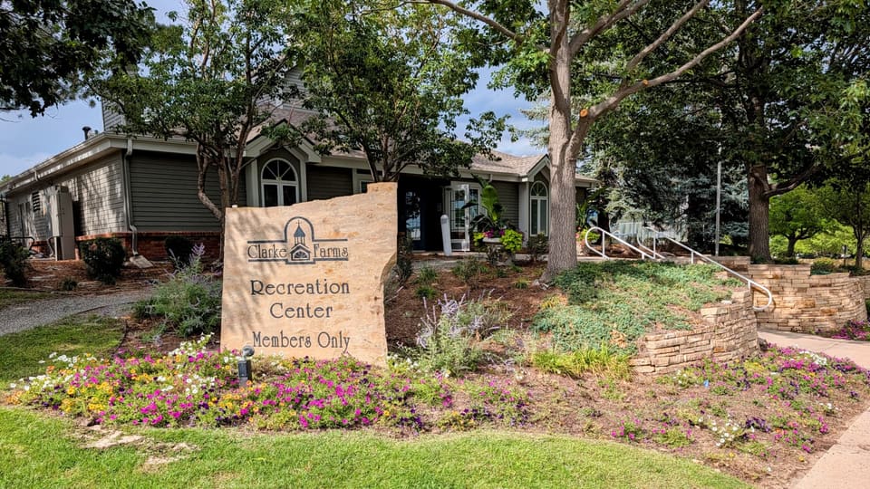 Clarke Farms Recreation Center entrance with stone sign and flower beds
