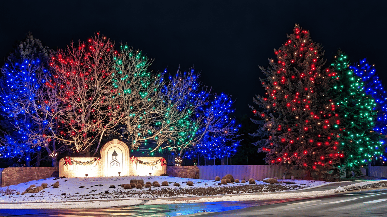 Clarke Farms entrance glowing with red, green, and blue Christmas lights on a snowy evening